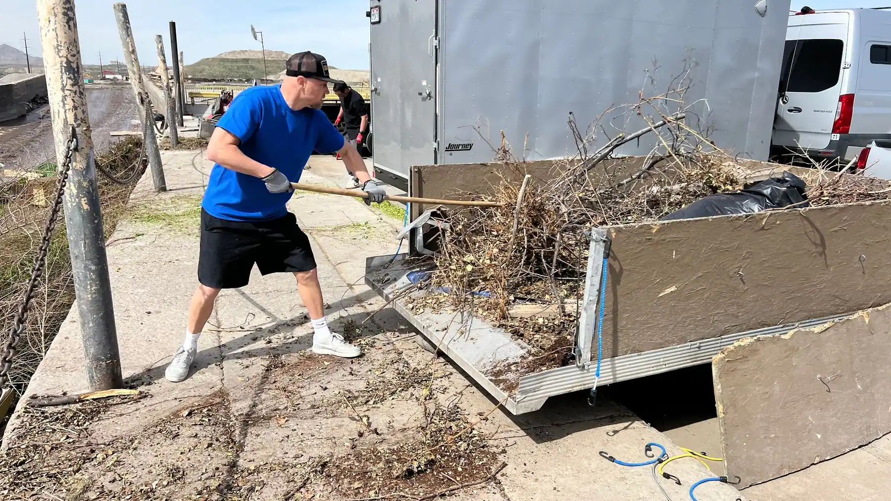 Jeremy raking brush and yard debris off his trailer at the transfer station