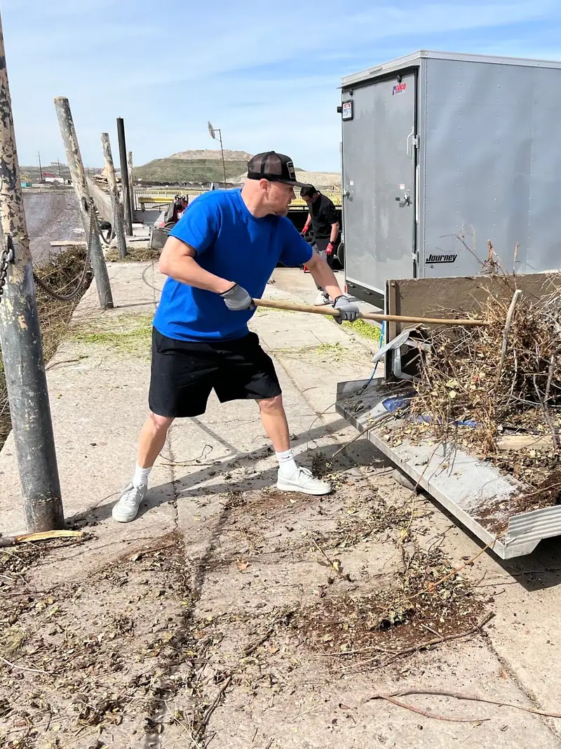 Jeremy raking brush off his trailer at the transfer station