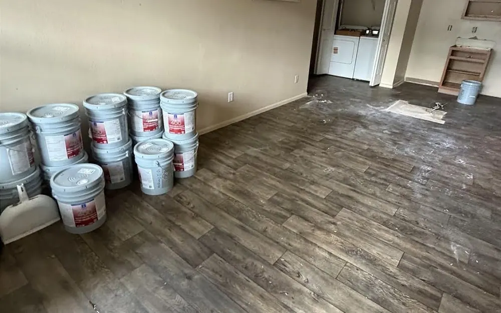 After: the same room with the couch, bags and boxes gone and the buckets still in place