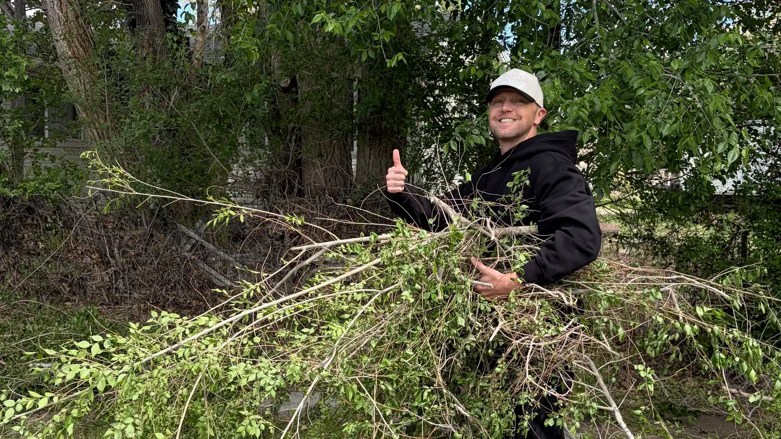 Jeremy hauling a pile of cut branches off a Salt Lake Valley lawn