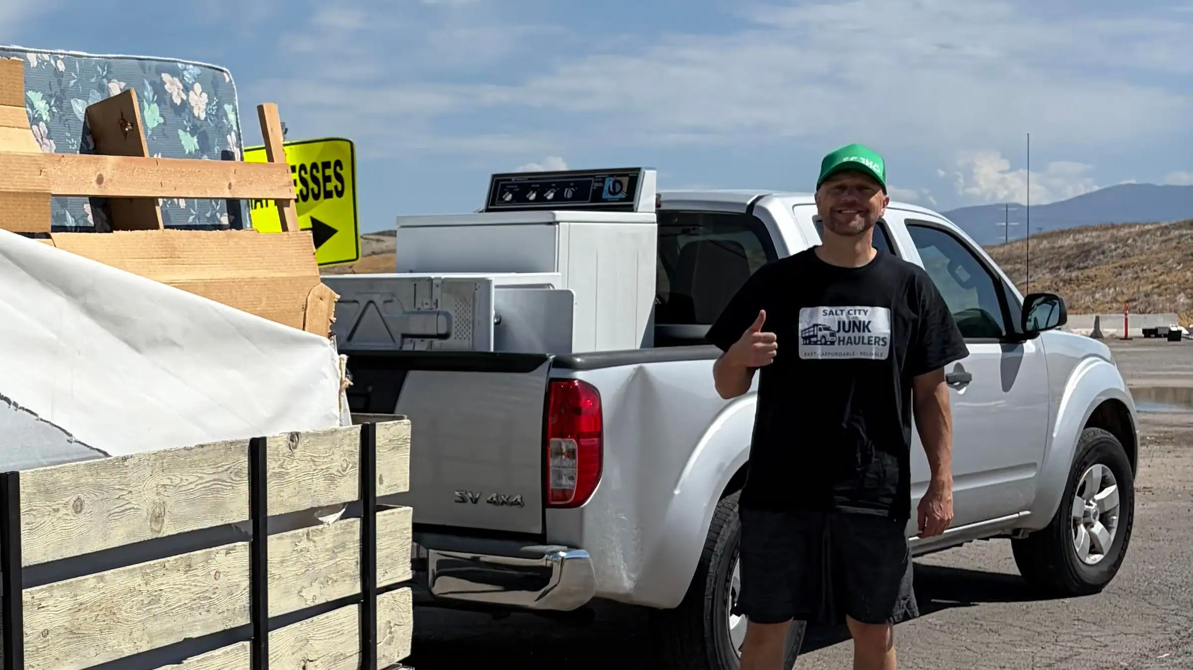 Jeremy beside his pickup at the transfer station with an old washer and a steel appliance door loaded in the bed