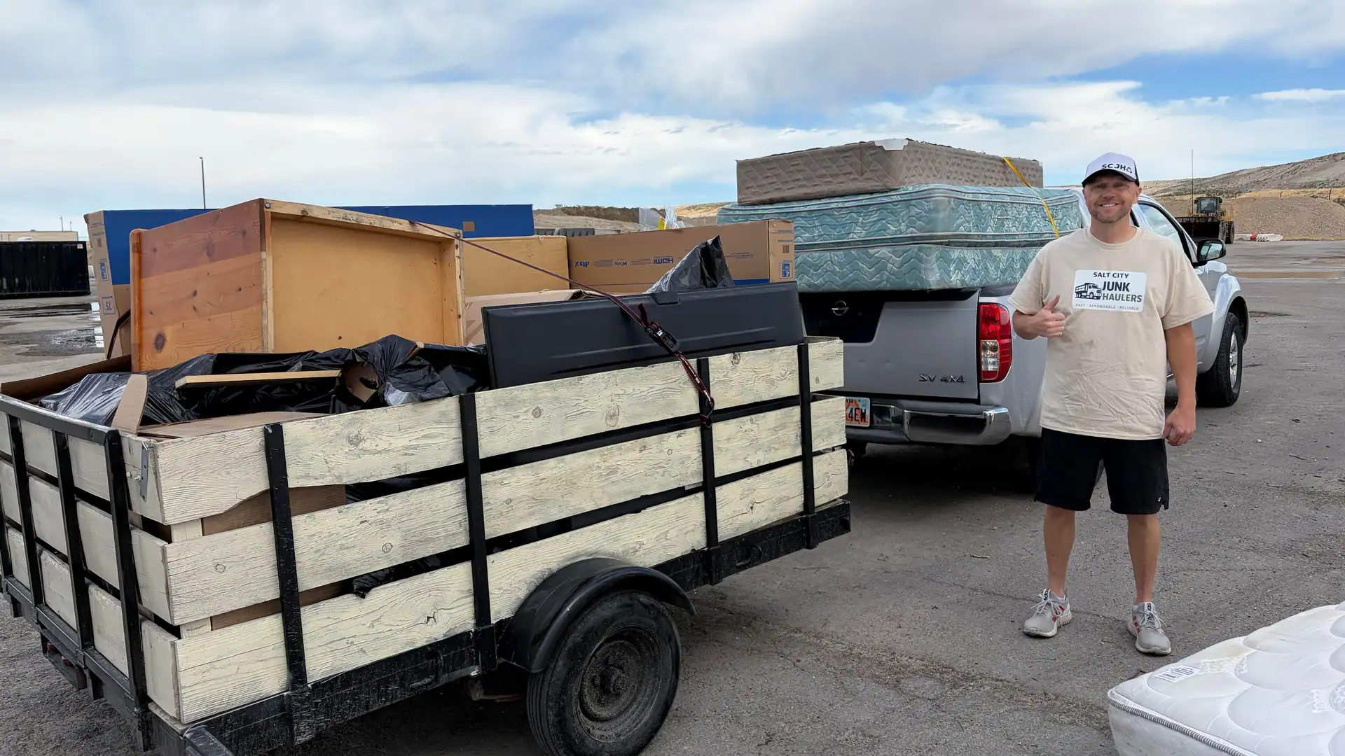 Jeremy at the transfer station with the pickup and trailer loaded with a cabinet, mattresses, and bags