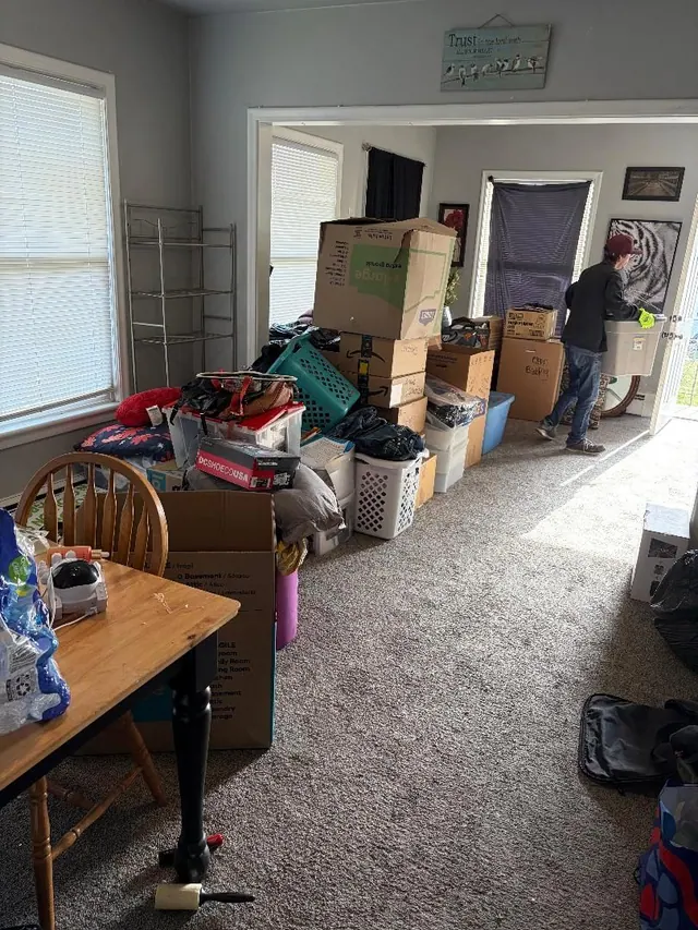 Living room stacked with moving boxes and bins before a move-out cleanout