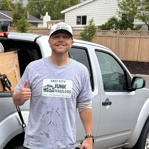 Jeremy in his gray Salt City Junk Haulers tee next to the loaded pickup